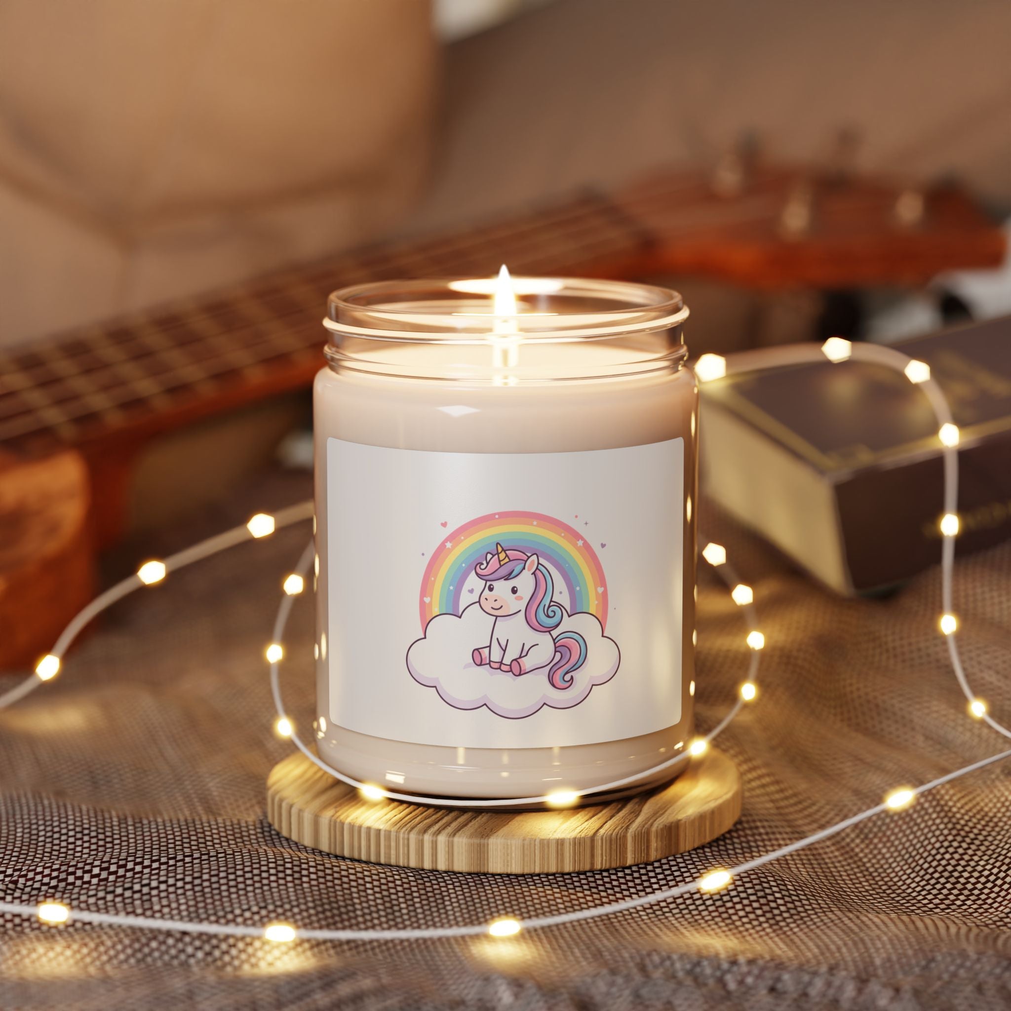 Candle in a glass jar with a label featuring an owl and moon design, surrounded by string lights and a guitar in the background.