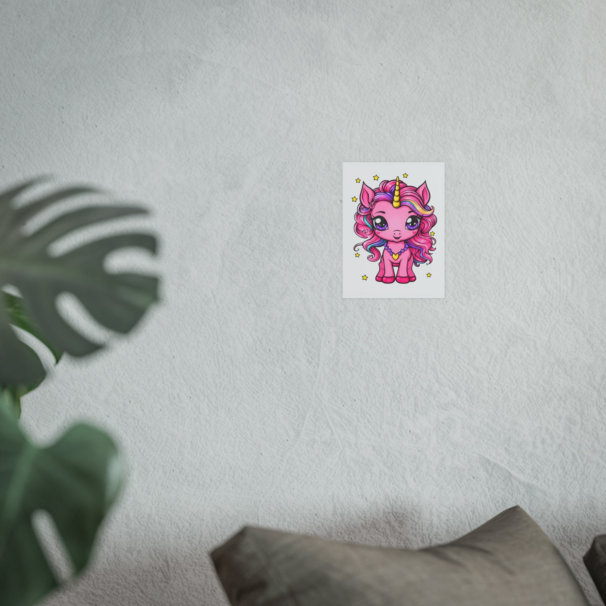 Framed artwork on a wall with a plant and cushion in the foreground