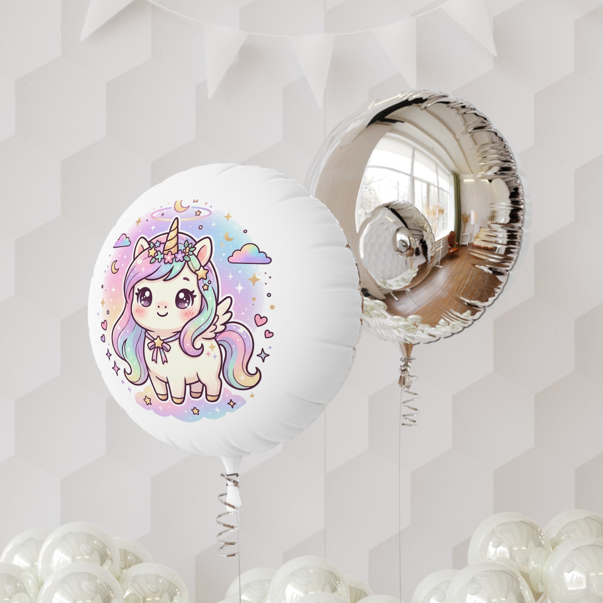 A round white foil balloon printed with a cute pastel unicorn illustration, shown next to a metallic silver foil balloon, with more white balloons at the bottom against a light gray geometric wall background.