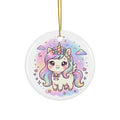 Round white ceramic Christmas ornament featuring a cute chibi-style unicorn with pastel rainbow hair, a gold horn, and a floral crown, hanging from a gold string against a white background.